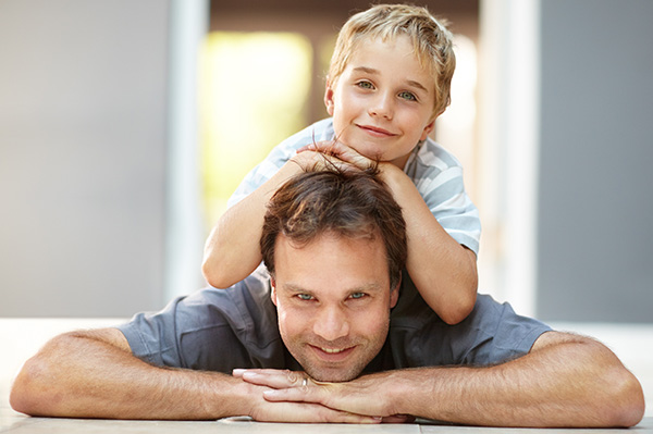 Man lying on the floor with his son on his back smiling
