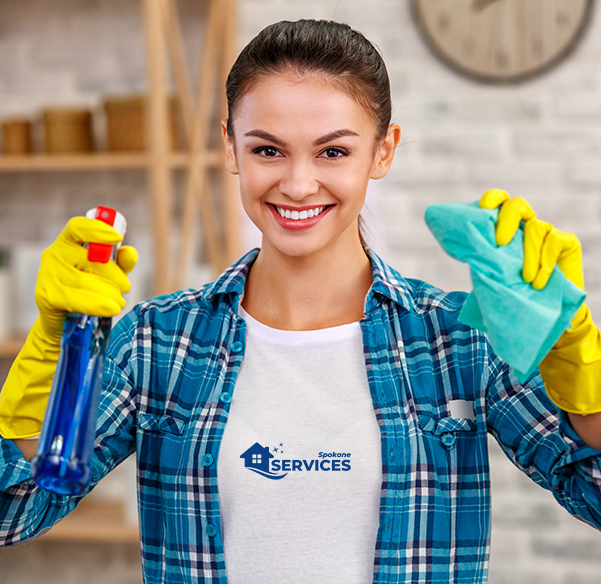 Smiling cleaning services worker in yellow rubber gloves holding a rag and a glass cleaner