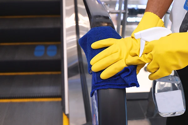 Cleaning worker in yellow gloves cleaning the escalator